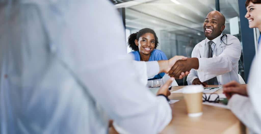 Shot of doctors shaking hands during a meeting in a hospital.