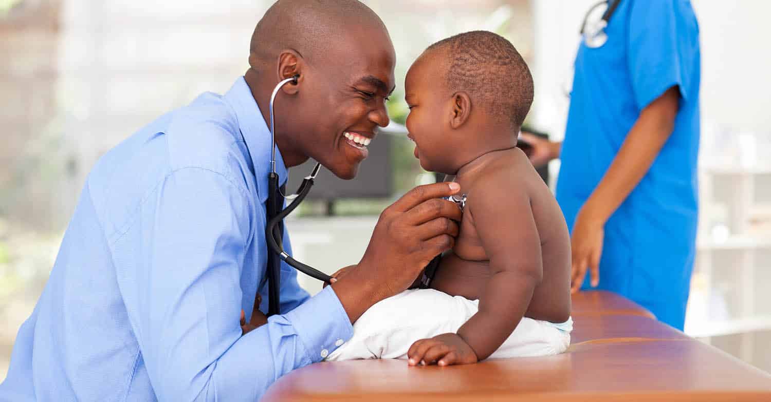 happy doctor examining baby boy with nurse in background